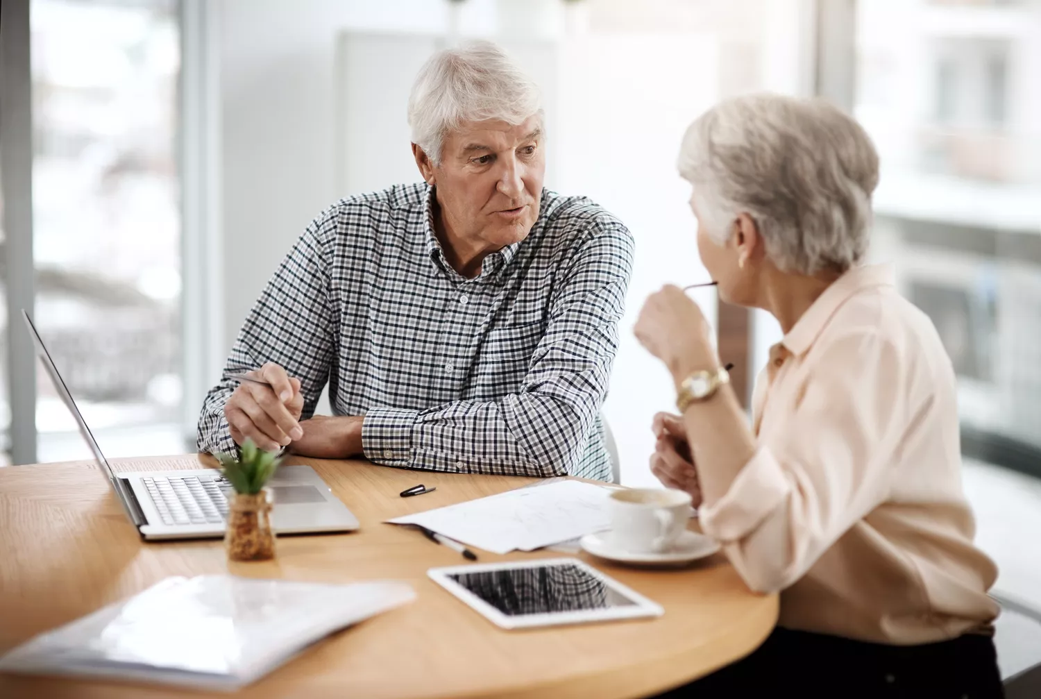 Retired couple talking about financial matters at a home table with a laptop